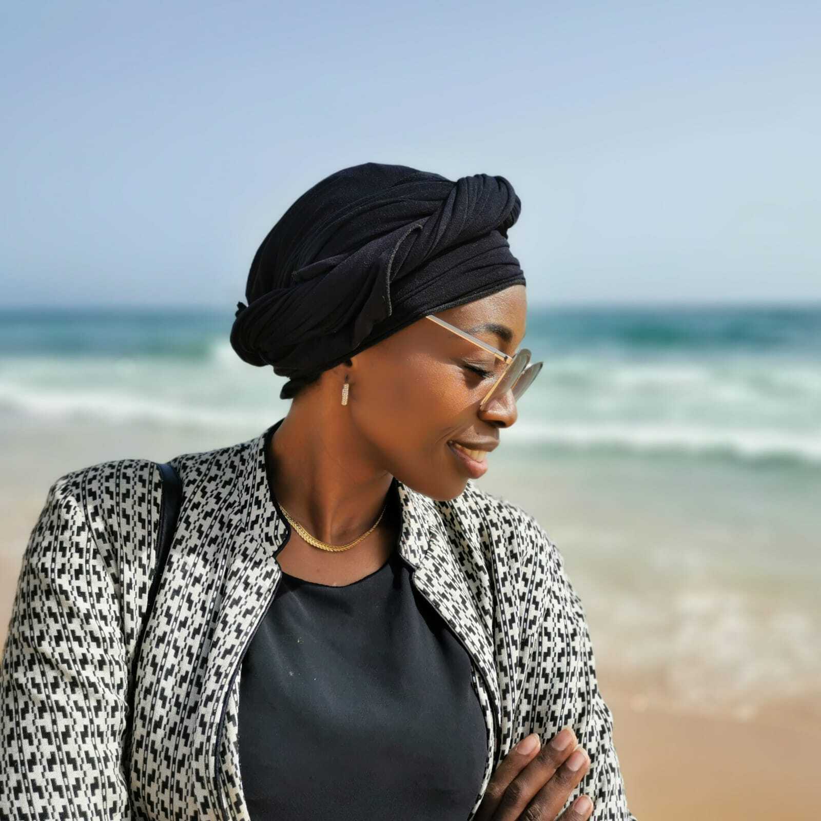 Portrait d'une architecte à Dakar, posant en bord de mer avec élégance.